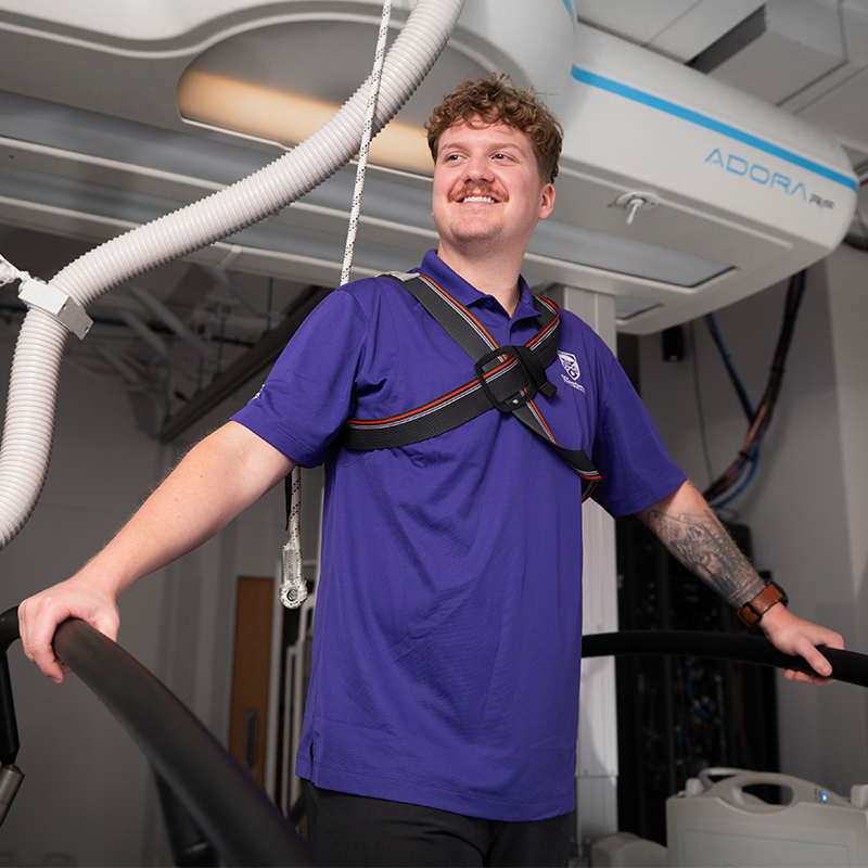 A student standing at some research equipment.