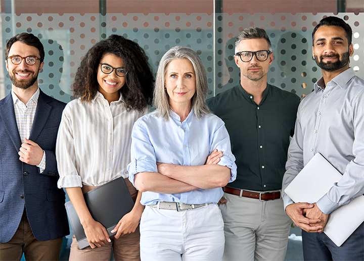 Five business professionals standing and smiling for the camera.